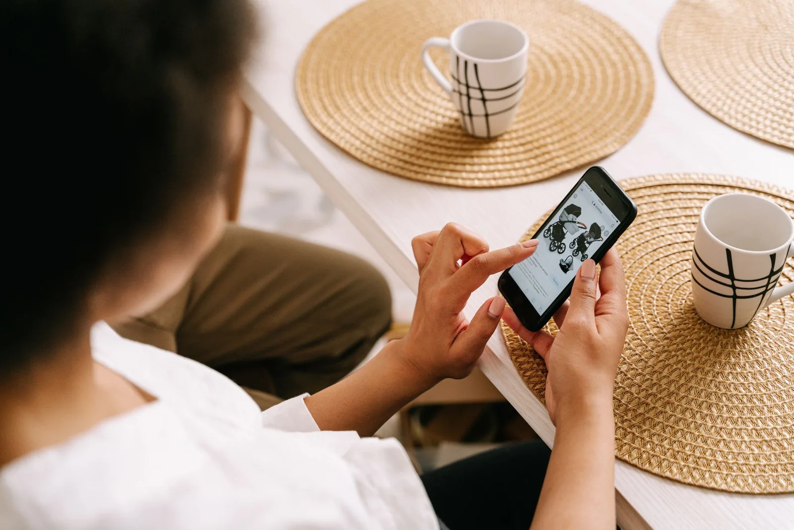 Person planning errands on a phone at a kitchen table, the kind of job an AI agent like Meta Muse takes on
